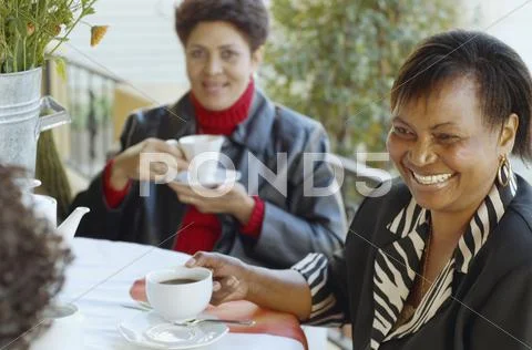 Multi-ethnic women having coffee outdoors Stock Photos
