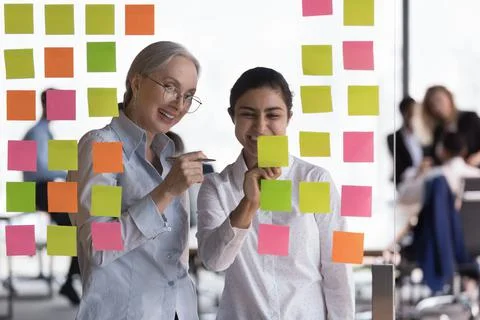 Multi ethnic workmates develop startup ideas writing on sticky notes Stock Photos