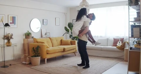 Multi-ethnic young couple jumping and affectionately hugging in an apartment Stock Footage 196119071