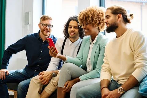 Multi-ethnic young people using mobile sitting on a coworking Stock Photos
