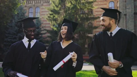 Multi ethnical friends graduates walking with their diplomas and in traditional Stock Footage 83601610