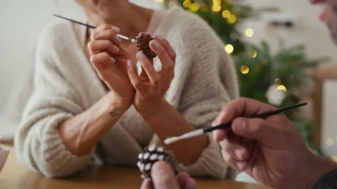 Multi ethnicity couple decorating cone with white paint during Christmas  Stock Footage 218782927