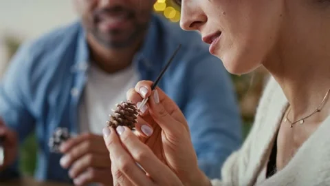 Multi ethnicity couple decorating cone with white paint during Christmas Stock Footage 218807388