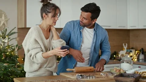 Multi ethnicity couple making a gingerbreads and using mobile phone Stock Footage 218778057