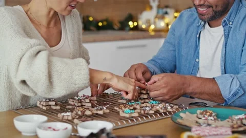 Multi ethnicity couple packing gingerbread cookies as small Christmas gifts Stock Footage 218779710