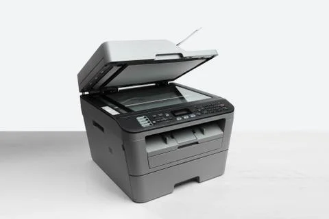 A multi function printer, copier, scanner on office table. gray wall behind Stock Photos