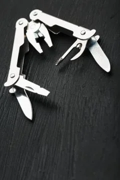 Multi-functional tool on a black textural background. 库存照片