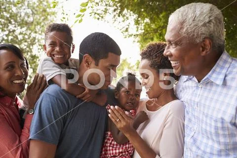 Multi Generation Black Family Look At Each Other In Garden