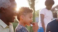 Multi Generation Black Family Sitting And Eating At Barbecue Stock Footage
