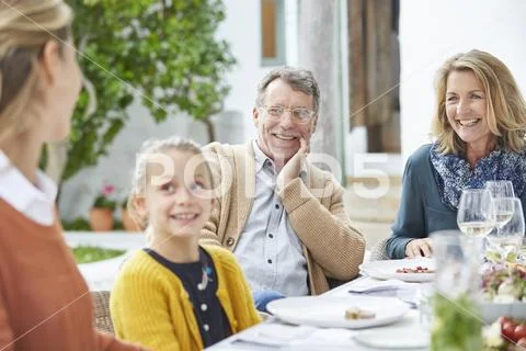Multi-generation family enjoying lunch at patio table Stock Photos