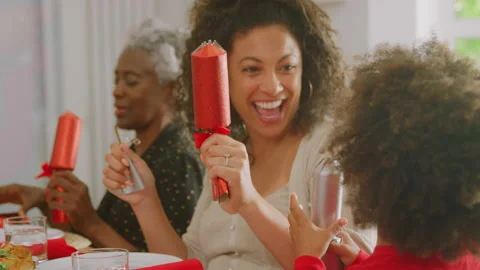 Multi generation family sitting around table at home pulling crackers before Stock Footage 160747073