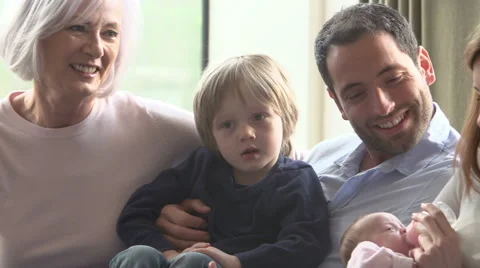 Multi Generation Family Sitting On Sofa With Newborn Baby Stock Footage
