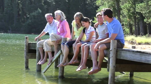 Multi-Generation Family Sitting On Wooden Jetty By Lake Stock Footage