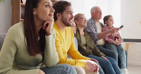 Multi generation family watching TV together on sofa, smiling and relaxed at Stock Footage 341936847