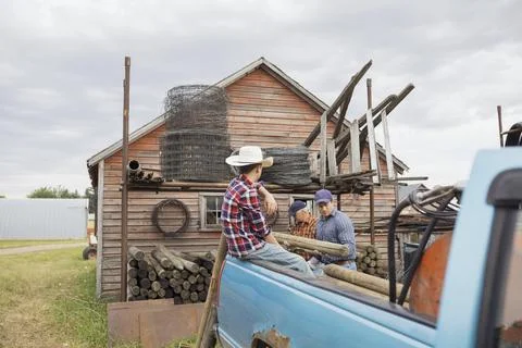 Multi-generation men loading logs onto truck on farm Stock Photos
