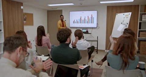 Multi generational business team engaging in a presentation with graphs and Stock Footage 274956182