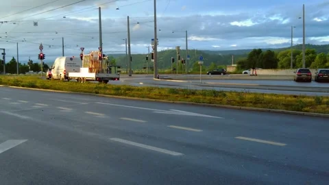 Multi lane city road at dusk with moving vans, cars and people on electric Stock Footage 334865468