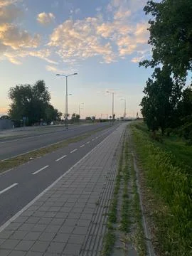 Multi-lane road parallel to sidewalk bike path under cloudy sky at dusk Stock Photos
