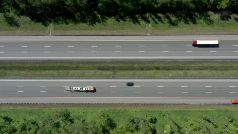 Multi-lane roads surrounded by green trees, pan shot of a highway drone aerial 스톡 동영상 133067655