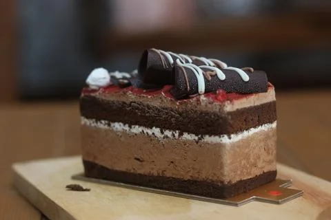 A multi layered chocolate cake sits on a wooden board with a metal cake teste 库存照片