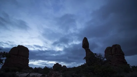 Multi-layered clouds flow past Balanced Rock in an Arches timelapse Stock Footage 107693268