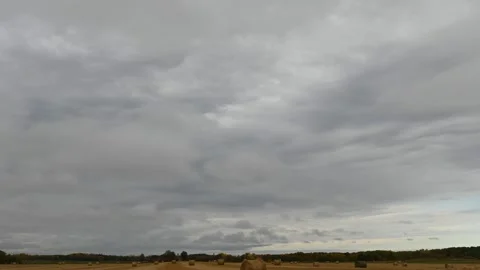Multi layered white and gray clouds drift in several directions above a farm  Stock Footage 151834597