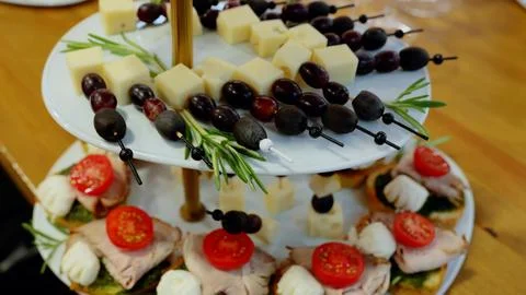 Multi level appetizer tray displaying skewered cheese, grapes, olives on upper Stock Photos