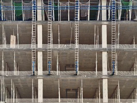 Multi level building facade under construction with protective safety netti.. Stock Photos