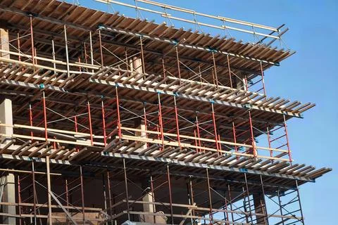Multi-level scaffolding on building under construction against blue sky 库存照片