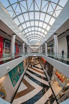 Multi-level shopping mall atrium with central skylight, vibrant banners, va.. Stock Photos