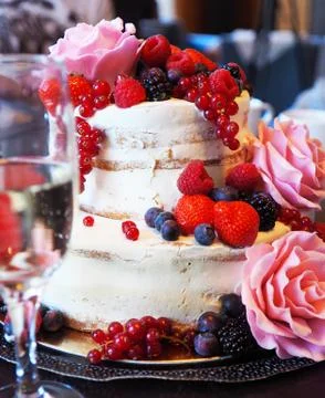 A multi level white wedding cake decorated with ripe bright berries and flowe Stock Photos