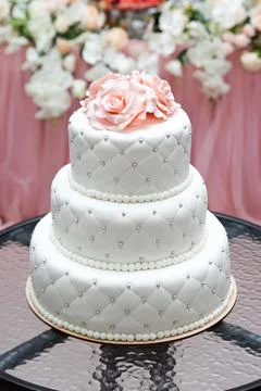 A multi level white wedding cake and pink flowers on top. Big cake. Stock Photos