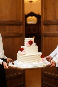 Multi level white wedding cake on a base and flowers on top Stock Photos