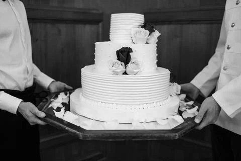 Multi level white wedding cake on a base and flowers on top Stock Photos