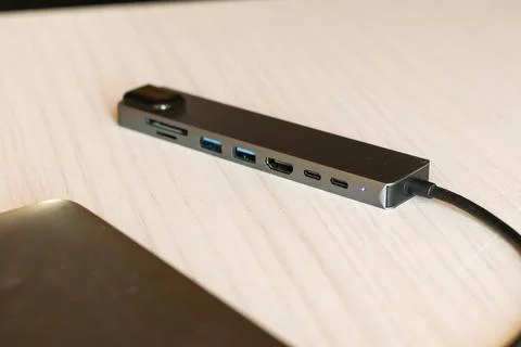 Multi-port USB-C hub with HDMI and USB slots attached to silver laptop Stock Photos