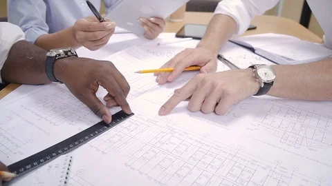 Multi race team of architects and engineers rewieving project blueprint in Stock Footage 98280355