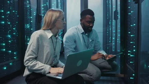 Multi-race team of server engineers using laptop digital tablet monitoring rack Video stock 119082392