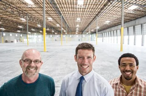 Multi-racial group of men standing in front of loading dock doors in a new empty Stock Photos