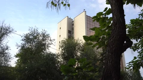 Multi-storey building against the sky with trees in the foreground Stock Footage 170487421