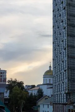 A multi-storey building under construction, a church, residential buildings. Stock Photos