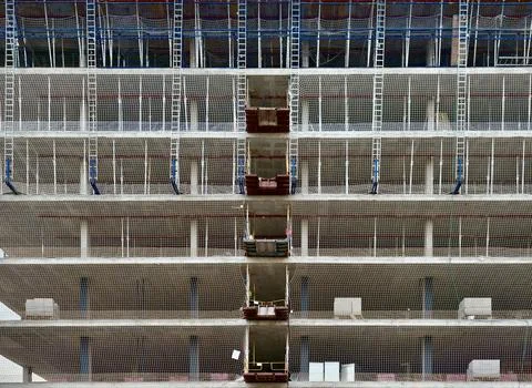 Multi-storey concrete construction facade wrapped with protective safety ne.. Stock Photos