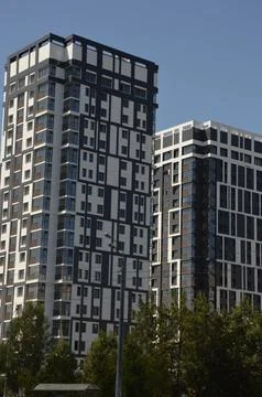 A multi-storey gray building standing against a blue sky. Modern high-rise re Stock Photos
