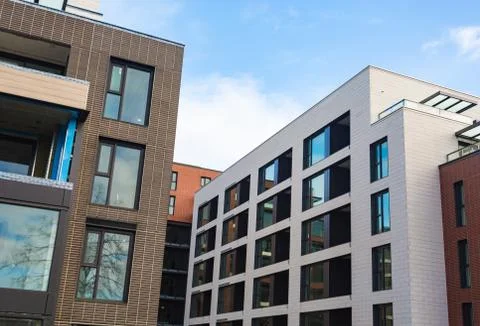 Multi-storey modern house close-up. Brickwork, windows, reflections of sky in Stock Photos