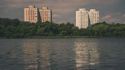 Multi-storey panel houses, overlooking a large pond and a dense park Stock Photos