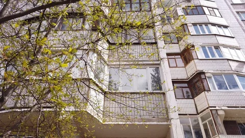 Multi-storey residential building behind tree branches in the city. Video stock 128855764