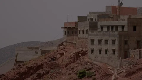 Multi-story concrete and earthen buildings cling to the jagged red rocky Vídeos de archivo 346106402
