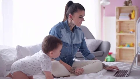 Multi tasking mother with baby son working at home  Stock Footage 75369733