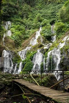 Multi-Tier Cascade Over Mossy Cliff with Wooden Walkway, Bali Stock Photos