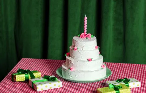 A multi-tiered cake and gift boxes on a checkered tablecloth on a backgroun.. Stock Photos
