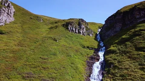 Multi-tiered waterfall cascading down mountain valley slopes Video stock 342337431